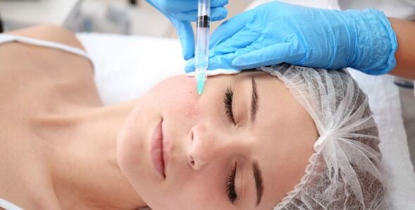 Un cosmetologo esegue una procedura di ringiovanimento della pelle del viso con il plasma